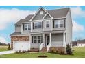 Charming two-story home showcasing stone accents, gray siding, and a welcoming front porch at 11640 International Dr, Middlesex, NC 27557