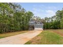 Charming two-story home featuring a blue exterior and a long driveway surrounded by lush trees at 125 Oswego Dr, Louisburg, NC 27549