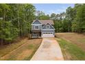 Beautiful two-story home with blue siding, a long driveway, and lush surrounding trees at 125 Oswego Dr, Louisburg, NC 27549