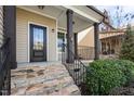 Inviting front porch with stone steps, dark wood columns and black metal railing for a touch of elegance at 130 Virginia Water Dr, Rolesville, NC 27571