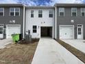 View of the rear of the townhome featuring a two-car garage and a concrete driveway at 1945 Plott Balsam Dr, Wendell, NC 27591