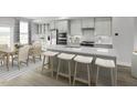 Bright kitchen features an island with seating, stainless steel appliances, modern cabinetry and adjacent dining area at 2875 Foster Woods Dr, Apex, NC 27502