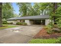 Charming exterior featuring a well-maintained lawn, mature trees, and a covered parking area at 402 Forest Rd, Oxford, NC 27565