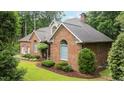 Traditional brick home featuring manicured landscaping, arched windows, and mature trees at 414 Bakewell Ct, Wake Forest, NC 27587