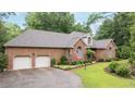 Traditional brick home featuring manicured landscaping, a two-car garage, and an American flag at 414 Bakewell Ct, Wake Forest, NC 27587