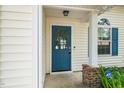 Close-up of a blue front door with glass panel and white trim, accented by brick base columns at 5006 Silhouette Dr, Durham, NC 27713