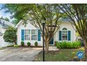 Inviting exterior view featuring white siding and blue shutters, complemented by lush landscaping and mature trees at 5006 Silhouette Dr, Durham, NC 27713