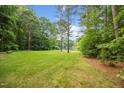 Expansive backyard with a large lawn, mature trees, and a peaceful view of the lake at 5344 Mill Dam Rd, Wake Forest, NC 27587