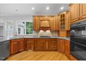 Well-lit kitchen featuring wood cabinets, hardwood floors, modern appliances, and a window overlooking the backyard at 5344 Mill Dam Rd, Wake Forest, NC 27587