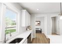 Bright, modern kitchen featuring white cabinetry, backsplash, and stainless steel sink with hardwood floors at 537 Folk Song Way, Wendell, NC 27591