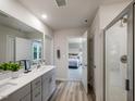 Modern bathroom with double vanity, quartz countertop, wood-look tile flooring, and a glass-enclosed shower with view to bedroom at 685 White Birch Ln, Angier, NC 27501