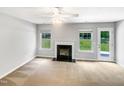 Empty living room featuring a fireplace, neutral carpet, and a view of the green backyard at 735 Sycamore Springs Dr, Fuquay Varina, NC 27526