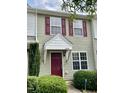 Inviting townhouse with a prominent front door, complemented by red shutters and manicured greenery at 7832 Averette Field Dr, Raleigh, NC 27616