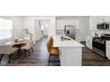 Open-concept kitchen with white cabinets, stainless steel appliances, and island with seating overlooking the dining area at 1007 Sora Way, Durham, NC 27703