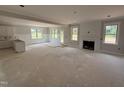 Open-concept living room with a fireplace, large windows, and adjacent kitchen space ready for customization at 145 Tee Dr, Selma, NC 27576