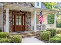Inviting front entry featuring a beautiful wood door, stone accents, and a quaint porch with columns at 286 Harrison Pond Dr, Pittsboro, NC 27312