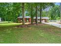 A charming brick home nestled among mature trees with a lush green lawn at 2968 Tram Rd, Fuquay Varina, NC 27526