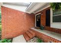 Close-up of a welcoming red brick front porch with black door and stylish plants at 2968 Tram Rd, Fuquay Varina, NC 27526