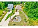 Aerial view of a yellow cottage-style home, landscaping, and driveway nestled among lush greenery at 2975 Carolyn Dr, Durham, NC 27703