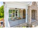 Inviting porch with cozy seating, ceiling fan and brick archway leading to the front door at 386 Monteith Dr, Chapel Hill, NC 27516