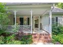 Inviting front porch with brick steps, white railings, and charming decorative lighting at 395 Timberlands Dr, Louisburg, NC 27549