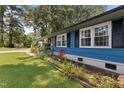 Side view of a blue home featuring vibrant landscaping with flowers and greenery at 509 Forest Ridge Rd, Garner, NC 27529