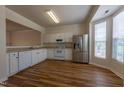 Bright kitchen featuring white cabinetry, stainless steel appliances, and durable laminate flooring at 5209 Echo Ridge Rd, Raleigh, NC 27612