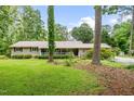 Inviting single-story home with a covered front porch, metal roof, and mature trees at 608 20Th St, Butner, NC 27509