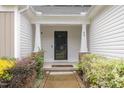 Close-up of a home's front entrance with a dark door framed by white pillars and lush landscaping at 65 Cattail Ln, Zebulon, NC 27597