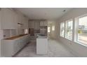 Bright kitchen featuring white cabinets, an island, and large windows for natural light at 7106 Hubner Pl # 44, Cary, NC 27519
