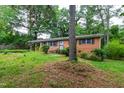 A brick home with black shutters and bars on the windows is surrounded by a green lawn and mature trees at 720 Sherrybrook Dr, Raleigh, NC 27610