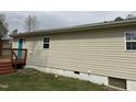 This is a side view of the home that features a deck, clean siding, and a basement door at 726 Thompson St, Pittsboro, NC 27312