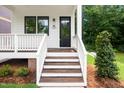 Charming front porch with wooden steps, white railings, and a glimpse of the lush greenery at 1621 Ella Wiggins Way, Raleigh, NC 27603