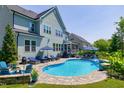 Beautiful backyard oasis featuring a luxurious pool with lounge chairs and umbrellas at 205 Silent Cove Ln, Holly Springs, NC 27540