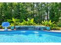 Tranquil pool waterfall feature surrounded by lush landscaping, creating a serene atmosphere at 205 Silent Cove Ln, Holly Springs, NC 27540