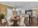 Dining area exhibits a round dining table with seating for four, decorative chandelier, and dark wood floors at 211 Westgrove Ct, Durham, NC 27703