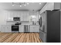 Modern kitchen features stainless steel appliances, white cabinetry, and wood flooring at 2913 Coxindale Dr, Raleigh, NC 27615