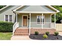 Inviting front porch with brick steps, white railing, and a beautiful wooden front door at 413 Top Greene Ln, Raleigh, NC 27601