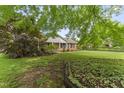 A traditional brick home sits surrounded by mature trees and a well-kept lawn at 6411 Pondview Ln, Durham, NC 27712