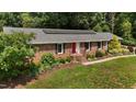 Brick home with well-maintained lawn and landscaping, complemented by solar panels on the roof at 825 Whispering Wind Rd, Burlington, NC 27217