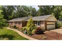 Well-manicured brick home with attached garage and lush, mature landscaping at 825 Whispering Wind Rd, Burlington, NC 27217