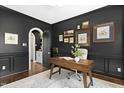 Stylish office with dark accent wall, hardwood floors, and door to small butler's pantry at 103 Saint Brides Ct, Cary, NC 27518