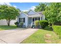 Inviting light blue home featuring a charming front porch, manicured landscaping, and concrete driveway at 1138 Ricochet Dr, Raleigh, NC 27610