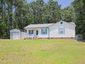 Exterior shot of charming single story home with white siding, blue shutters, and a detached garage at 117 Renee Dr, Smithfield, NC 27577