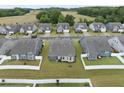 Aerial view of backyards in a well-manicured neighborhood, highlighting white fences, grass and neighboring homes at 129 Alumroot Rd, Holly Springs, NC 27540