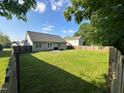 Large, grassy backyard with a wooden fence and partial view of neighboring houses at 201 Joe Gibson Dr, Gibsonville, NC 27249