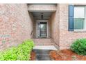 Inviting front entrance with brick facade, decorative plants, and classic black shutters at 2012 Muirfield Ct, Elon, NC 27244