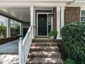 Charming brick home featuring a covered portico, black front door and landscaped entryway at 2212 Oxford Hills Dr, Raleigh, NC 27608