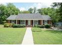 Charming brick home featuring a well-manicured front lawn and an inviting covered porch at 303 Spring St, Louisburg, NC 27549
