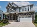 Charming two-story home showcasing a stone and siding exterior, lush landscaping, and a welcoming two-car garage at 359 Abbot Pl, Chapel Hill, NC 27516